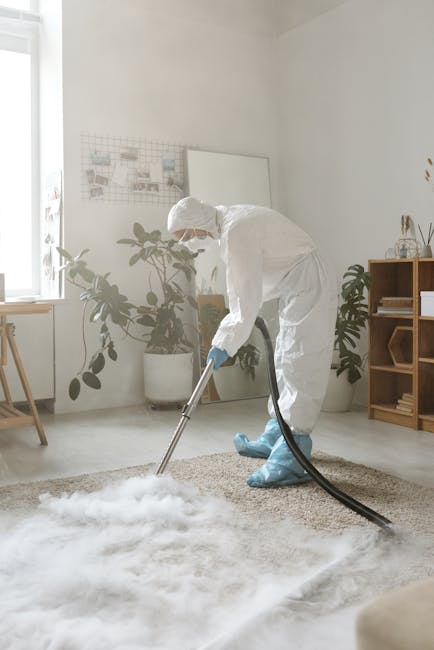 A professional cleaning technician from Leamouth Carpet Cleaners is performing deep surface cleaning in a bright, modern living room. The technician is dressed in a full white protective suit, gloves,